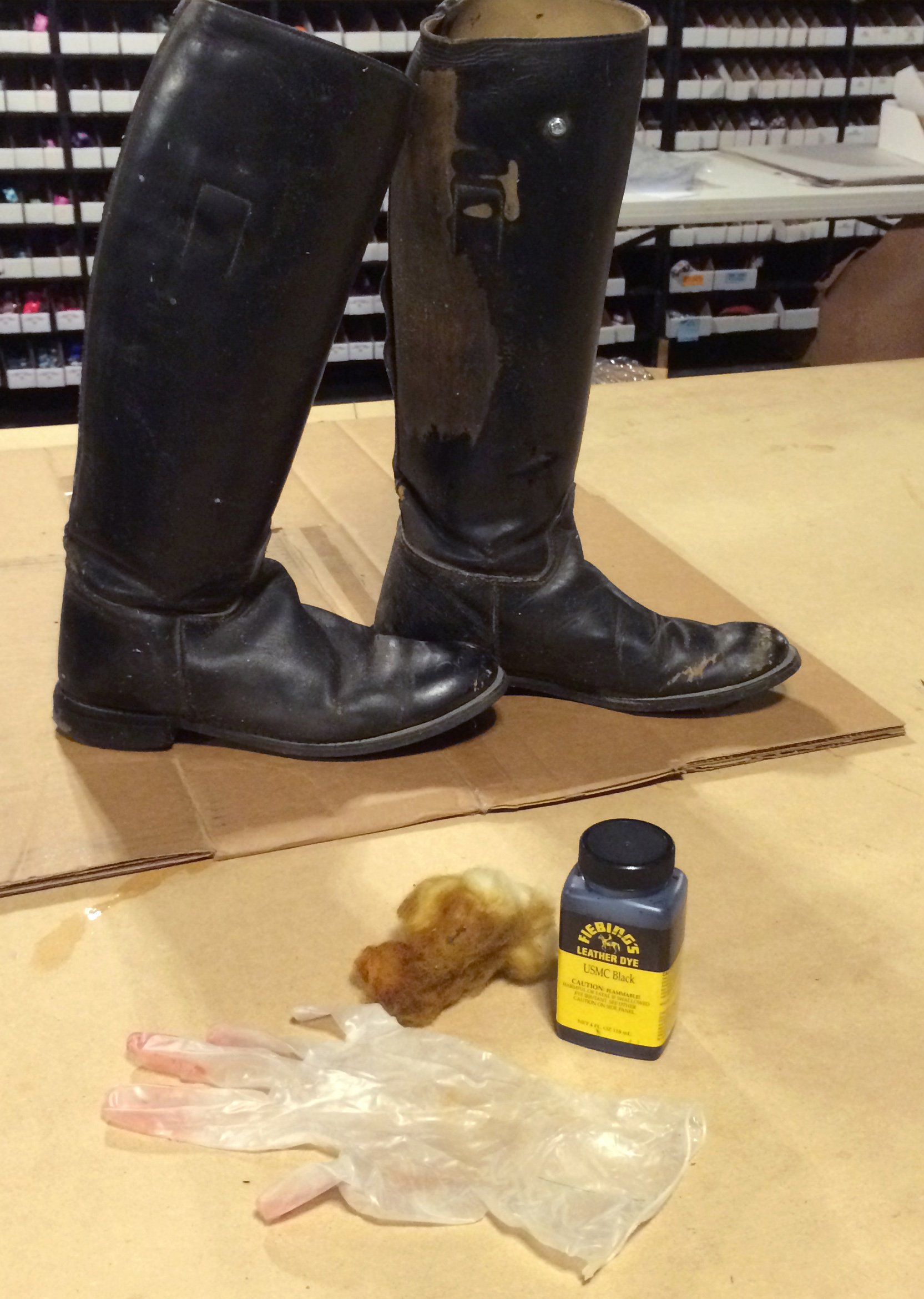 Worn leather boots on top of a protected surface, with supplies to restore them in the foreground.