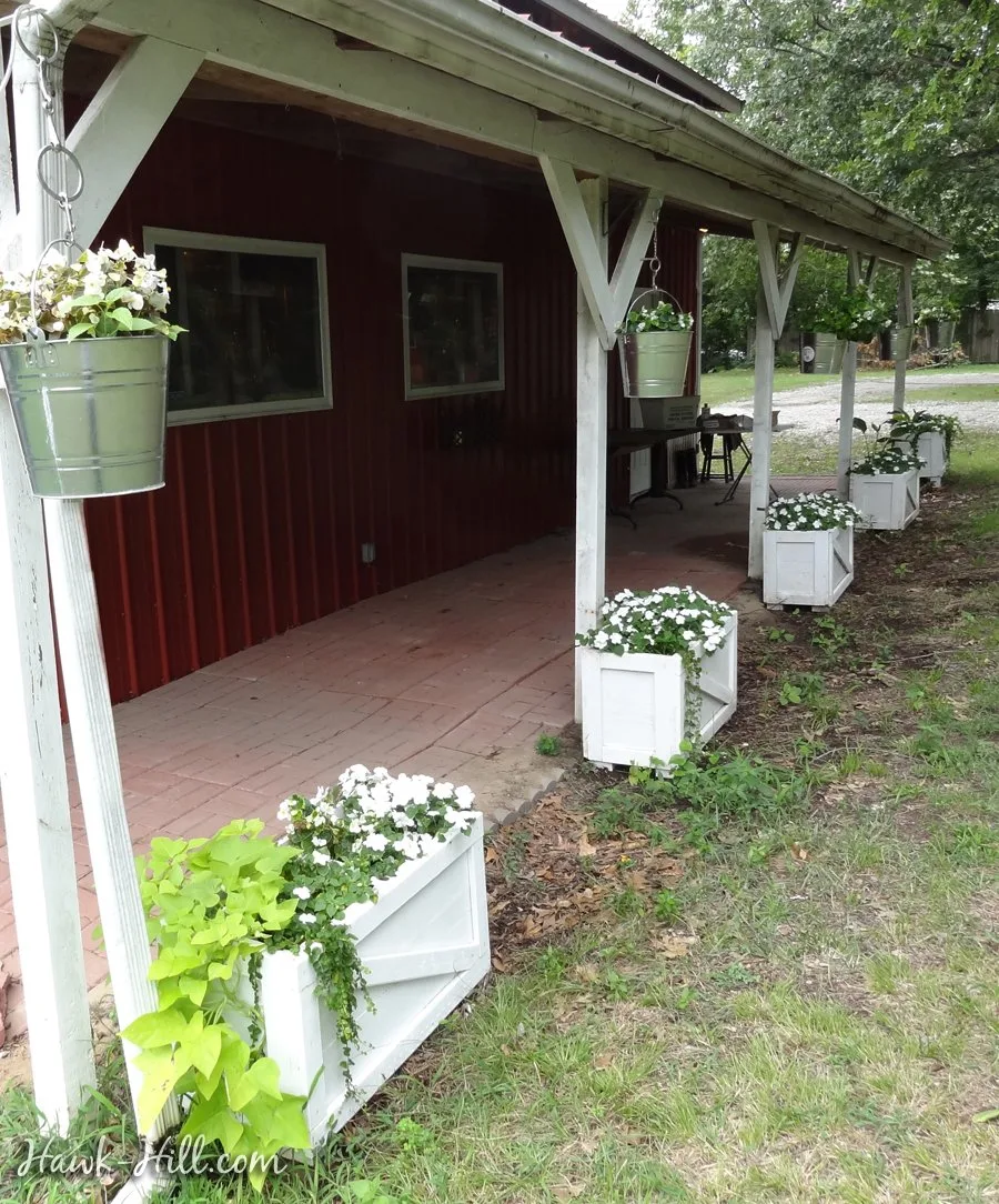 Ranch style porch with hanging "baskets" using buckets and planter boxes