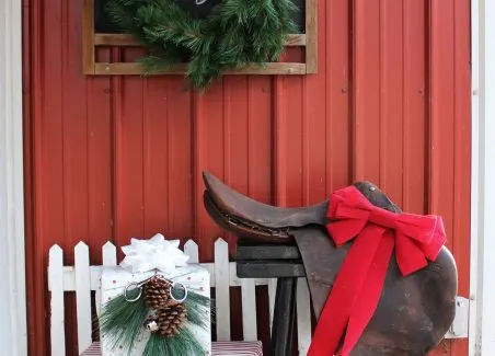 outdoor christmas decorations featuring equestrian english saddle, wrapped gifts, chalkboard, wreaths, silver bells, and snaffle bit