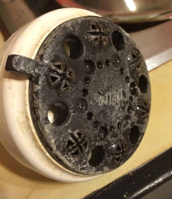 A shower head with a crust of mineral deposits.