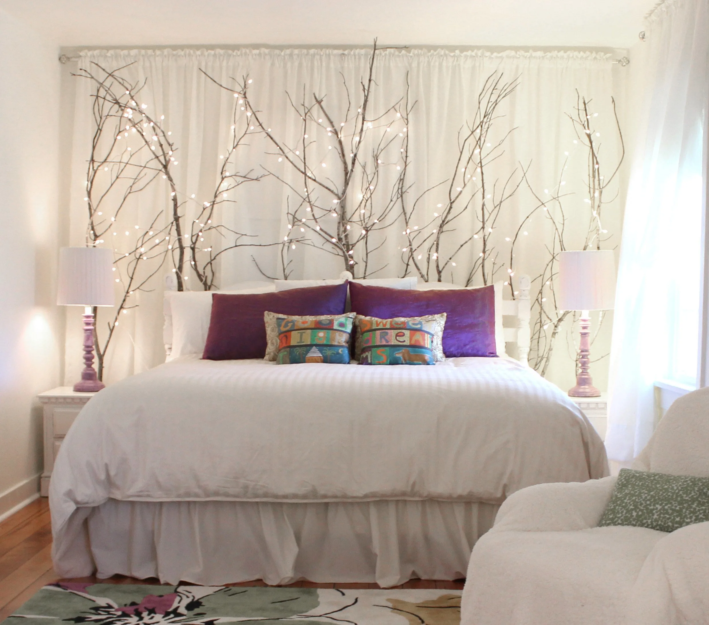 a bed with tree branches decorating the wall behind it and forming a headboard