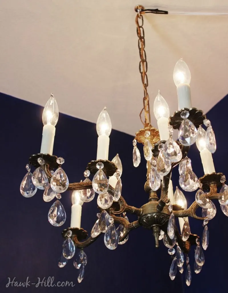 chandelier hung from a ceiling hook in an apartment with swagged cord