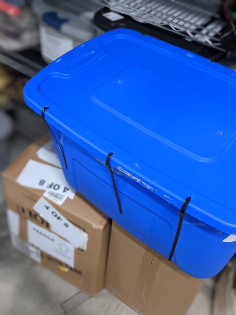 A blue storage tote with heavy duty zip ties sealing the container shut.