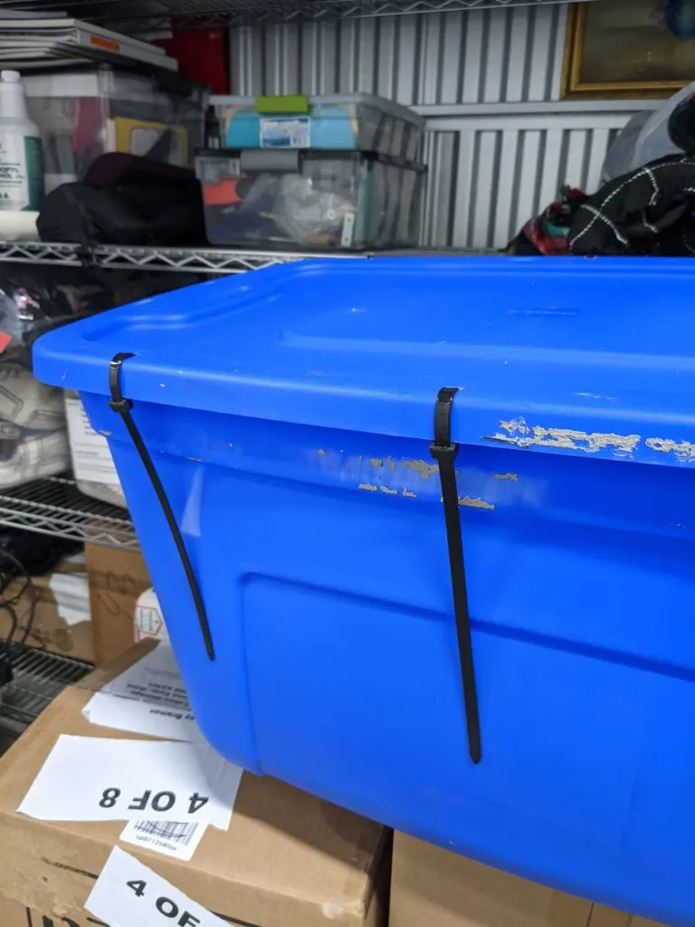 A blue storage tote with heavy duty zip ties sealing the container shut.