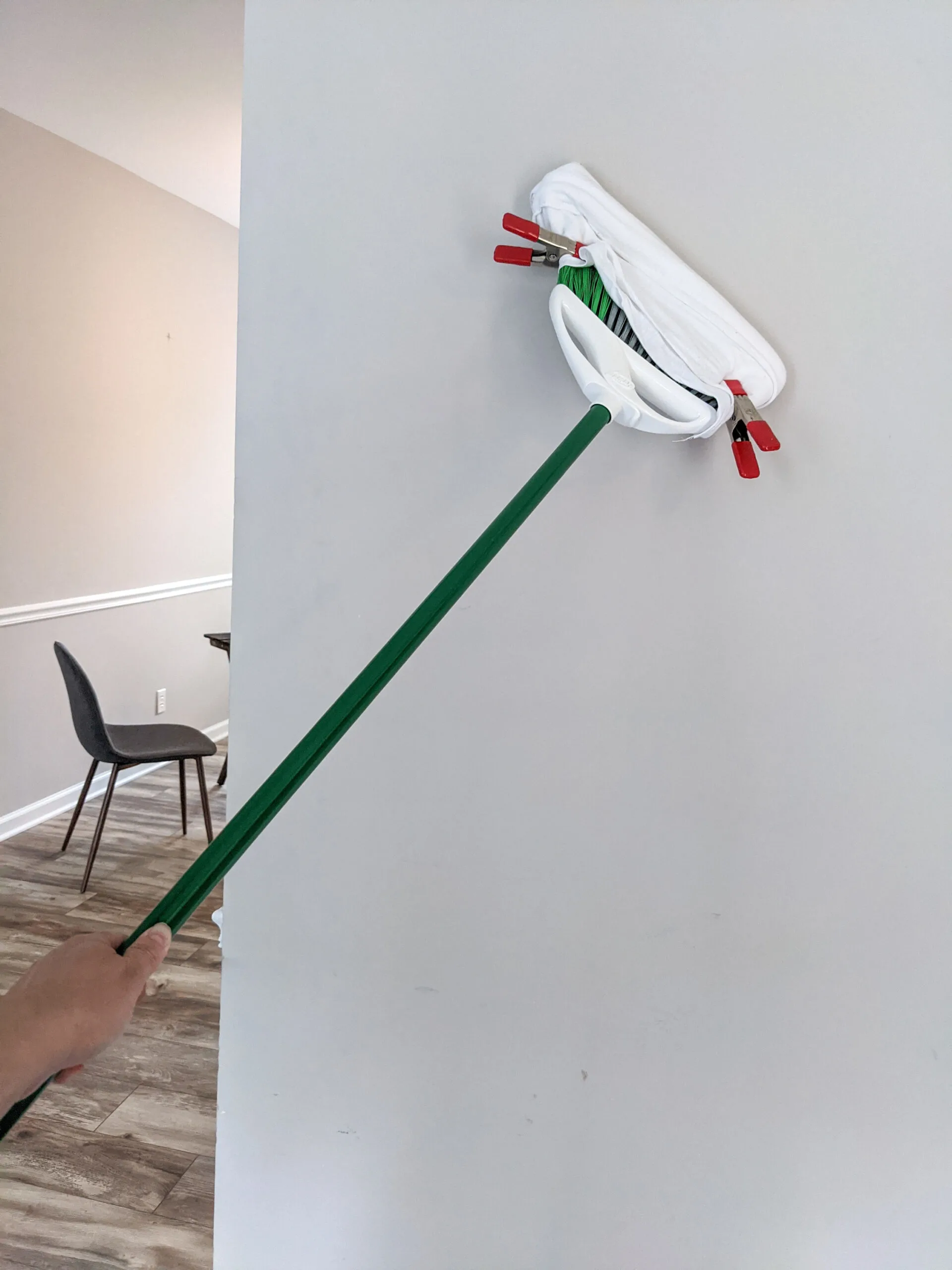 A wall being cleaned with a modified broom.