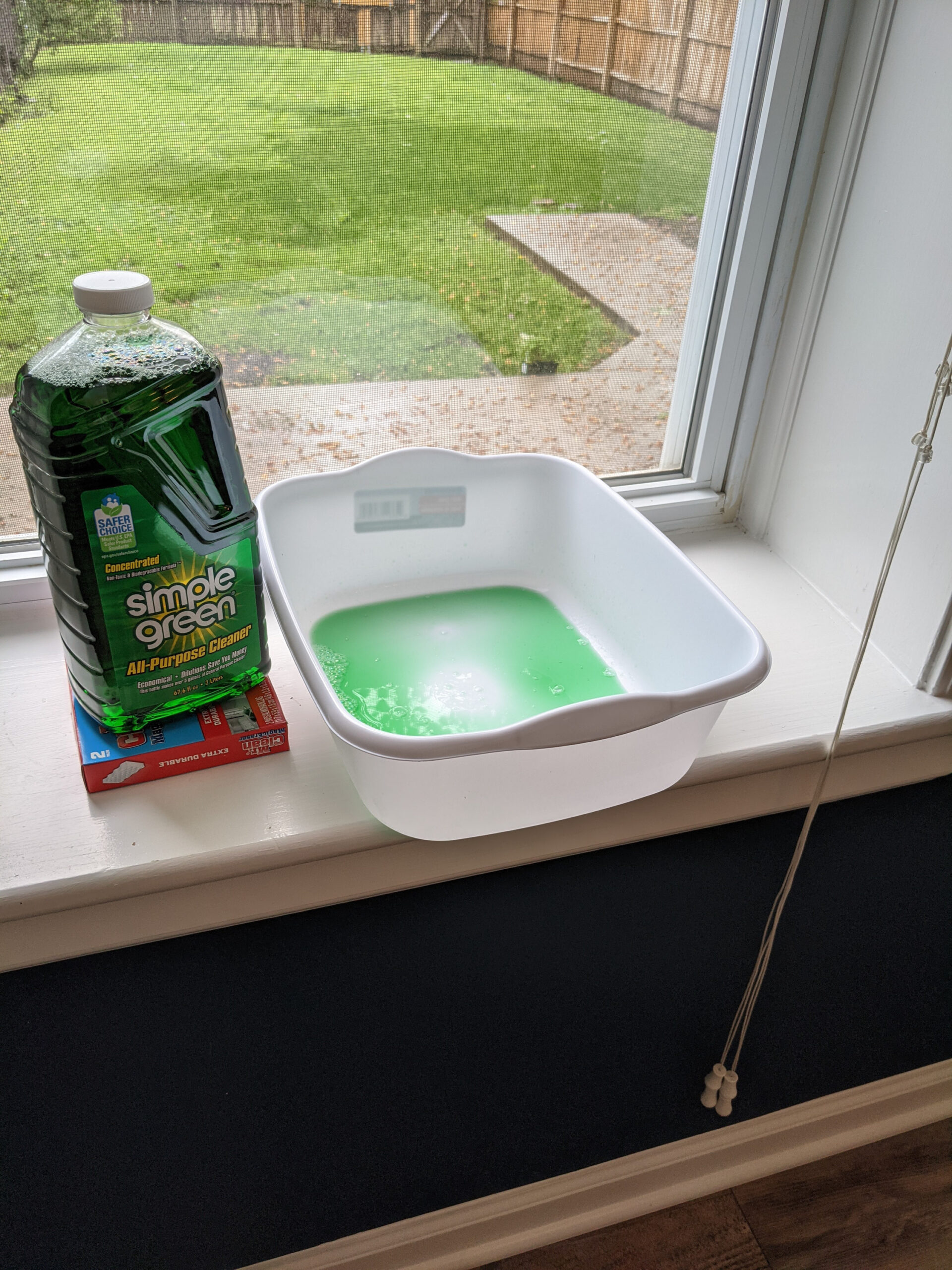 Green cleaning solution in a dishpan.