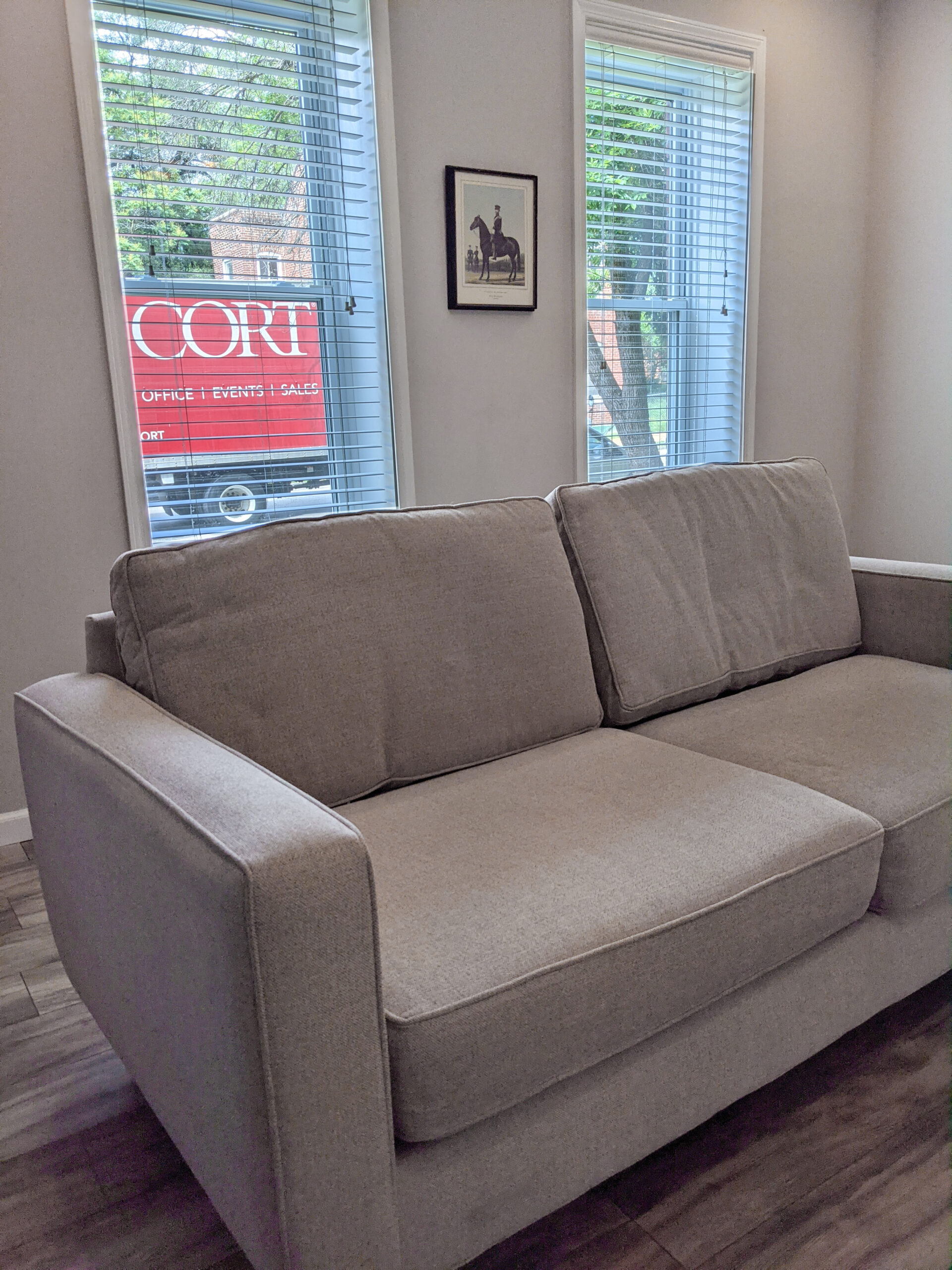 A used couch from the CORT outlet shortly after delivery, pictured with the CORT truck shown outside the window of the home.