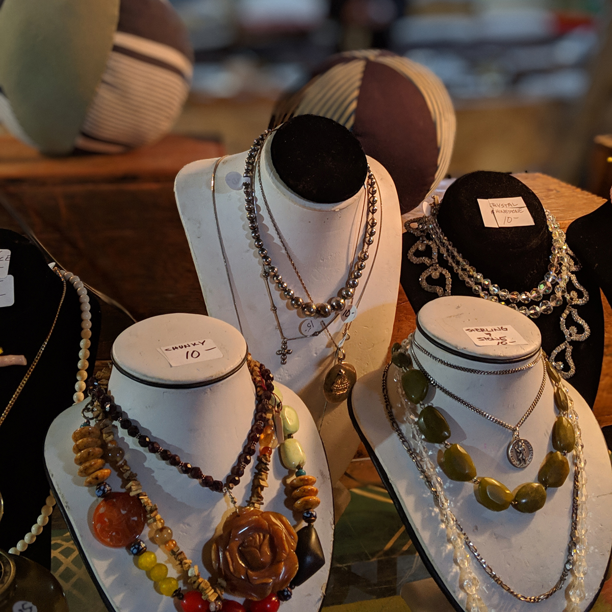 Necklaces on display on a table in a flea market booth.