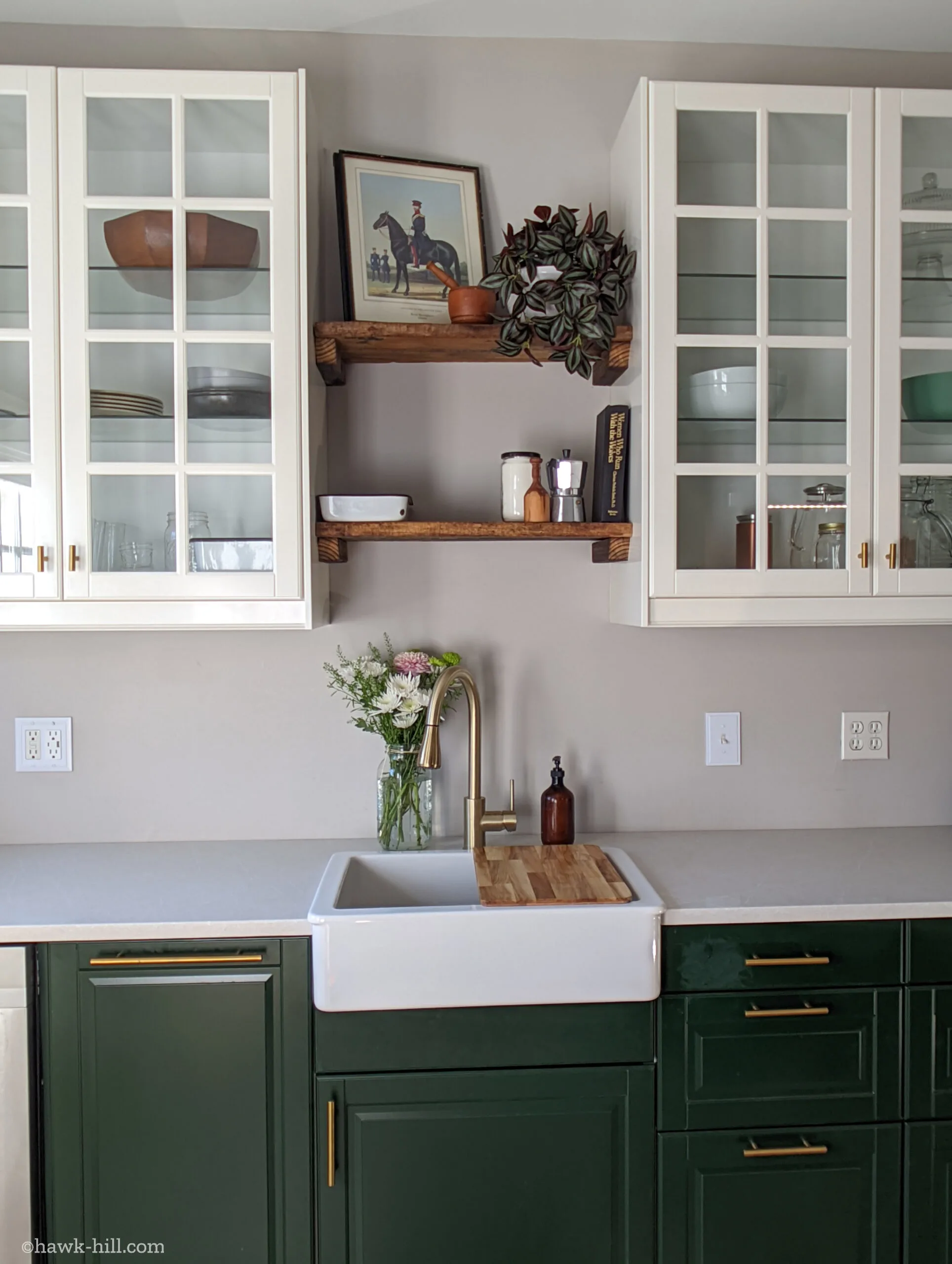 A green, white, and gray kitchen with natural wood open shelves.
