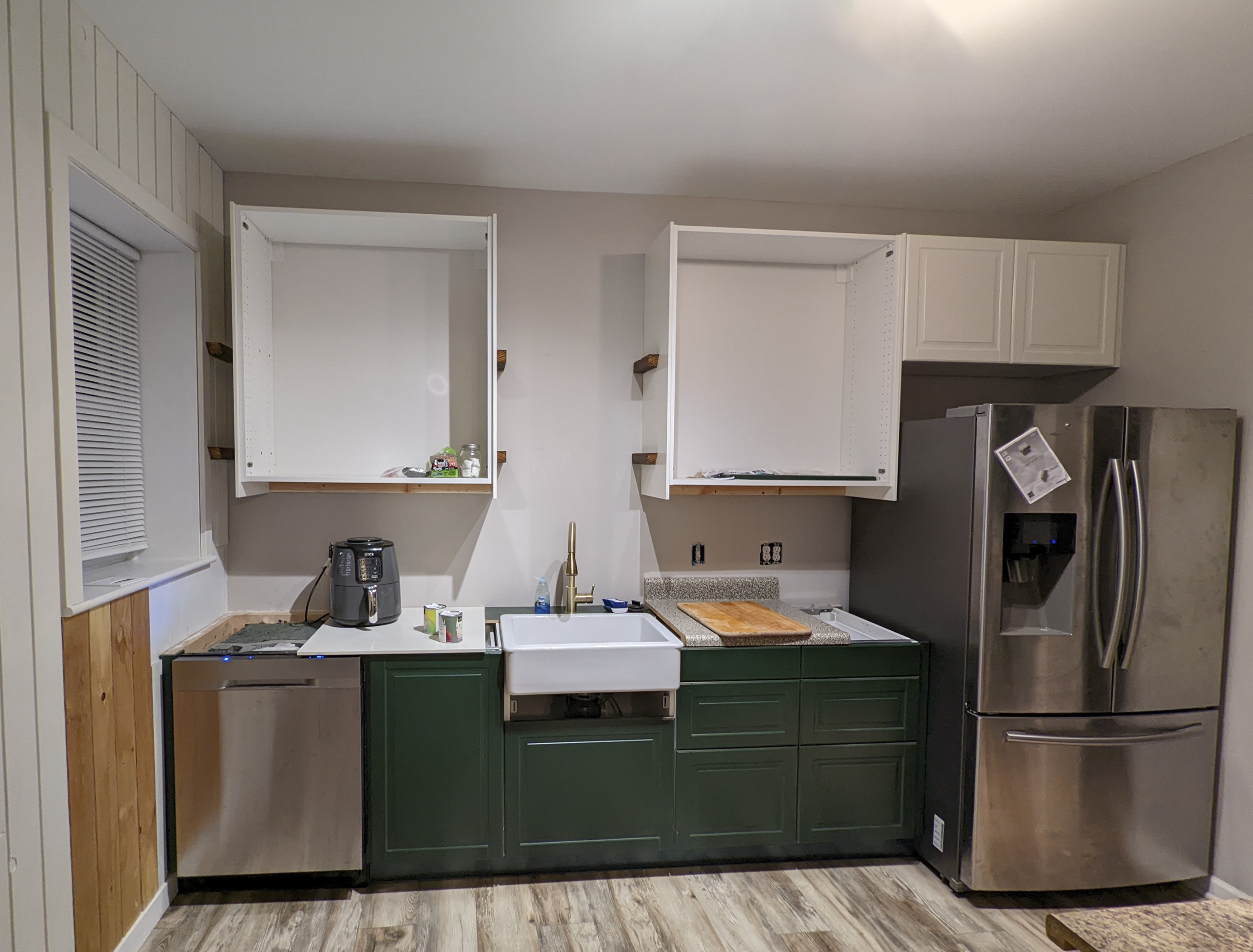 A green IKEA kitchen renovation in progress, shown with half finished cabinets.