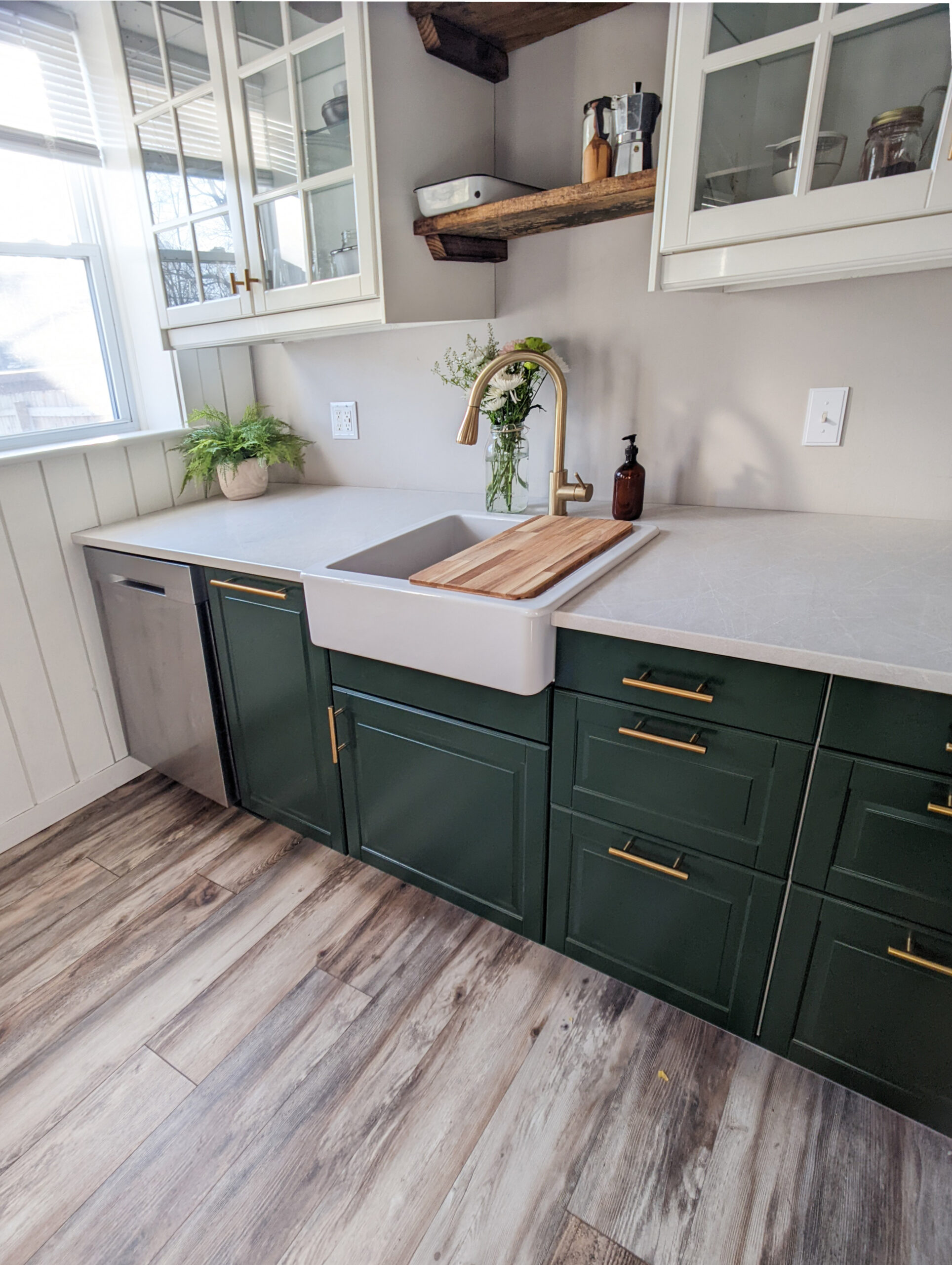 A small galley kitchen featuring open shelving, glass front cabinets, and green base cabinets.