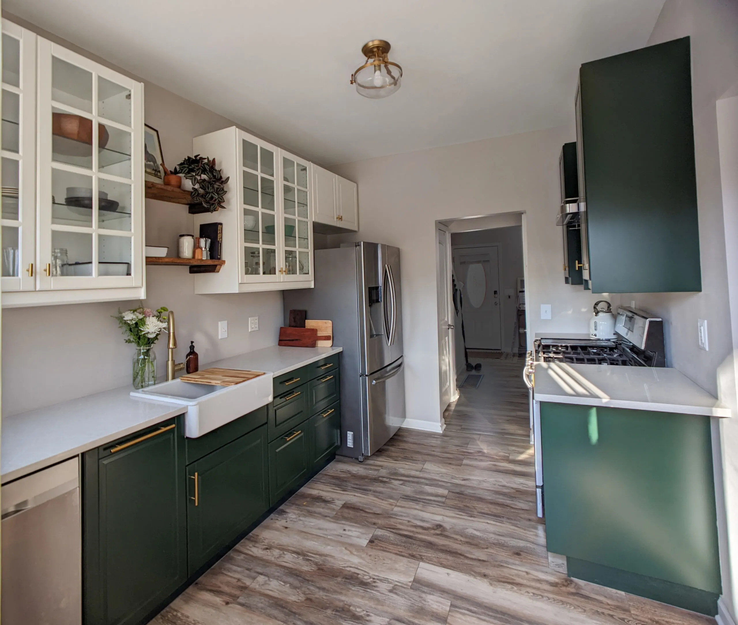 A small galley kitchen featuring open shelving, glass front cabinets, and green base cabinets.