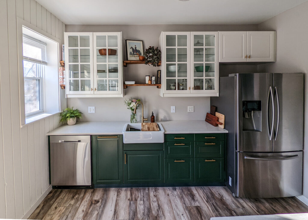 A modern kitchen remodel with traditional style: forest green lower cabinets with white glass uppers.