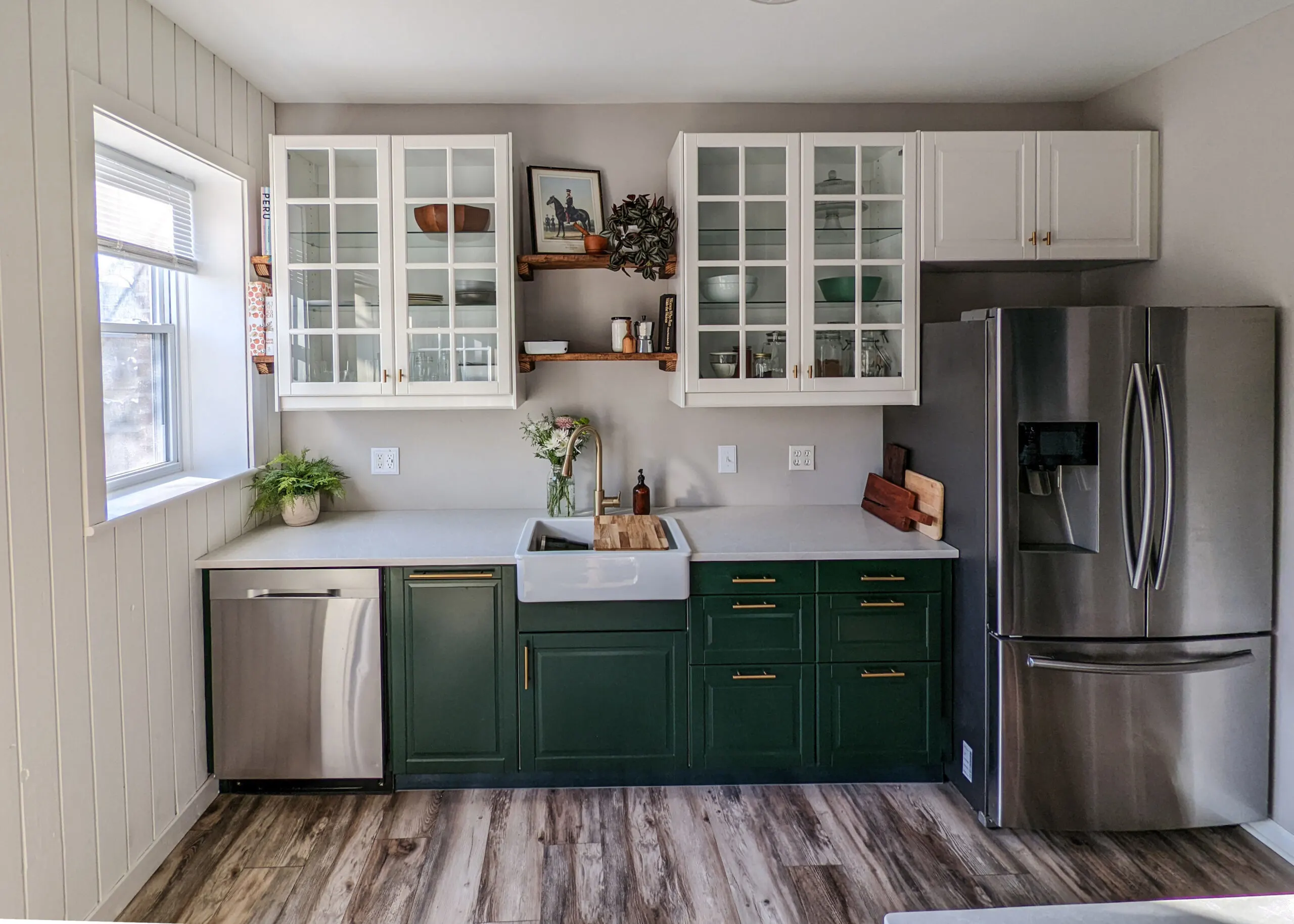 Stainless steel appliances paired with gold fixtures in a kitchen with green and white cabinets.