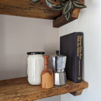 Items displayed on a set of open kitchen shelves made from reclaimed floor joists.