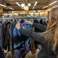 A woman holds up a vintage sweater at a thrift store, shortly after Goodwill restocked