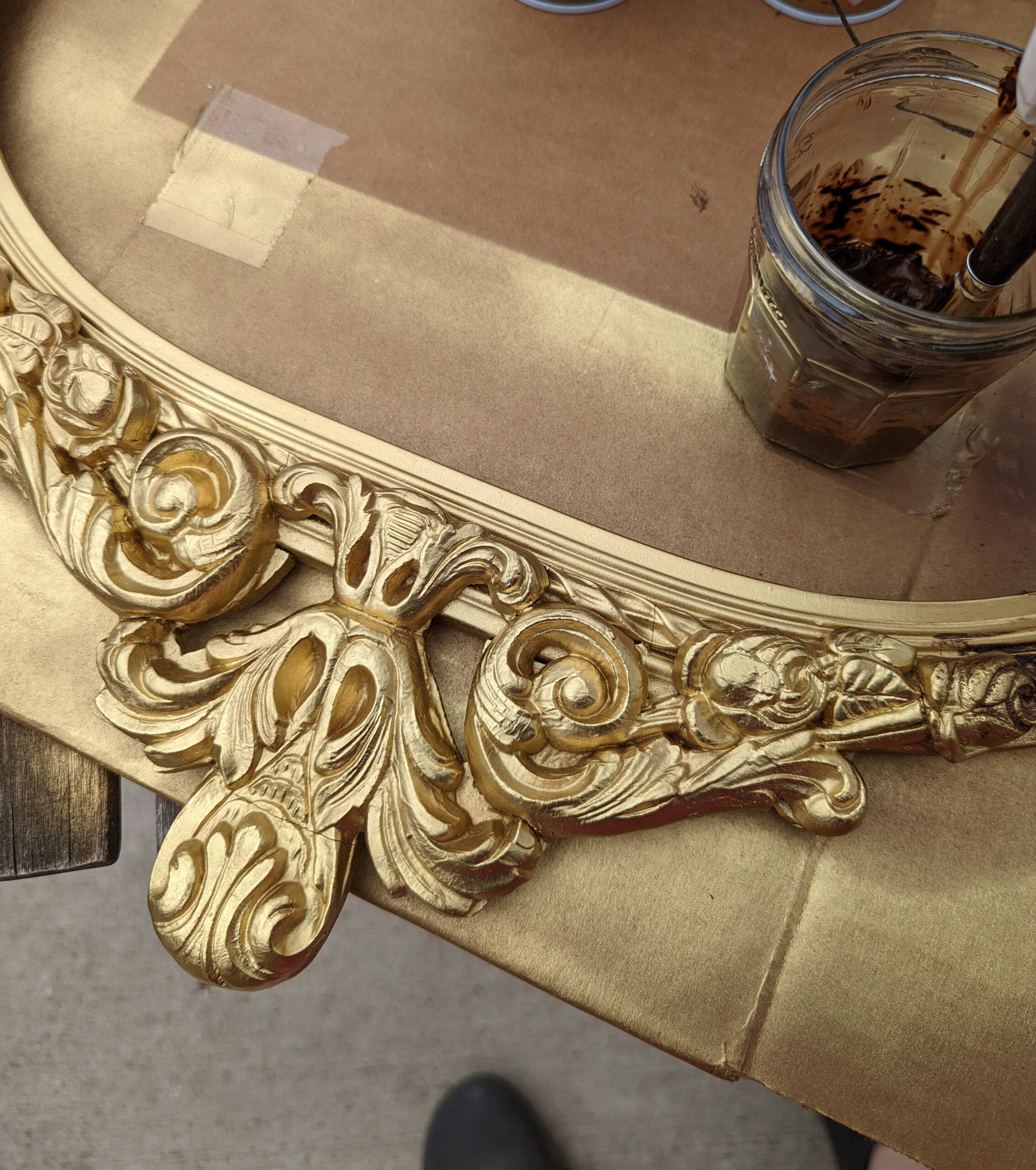 A closeup image of an antique frame being repainting with an antique gold finish.