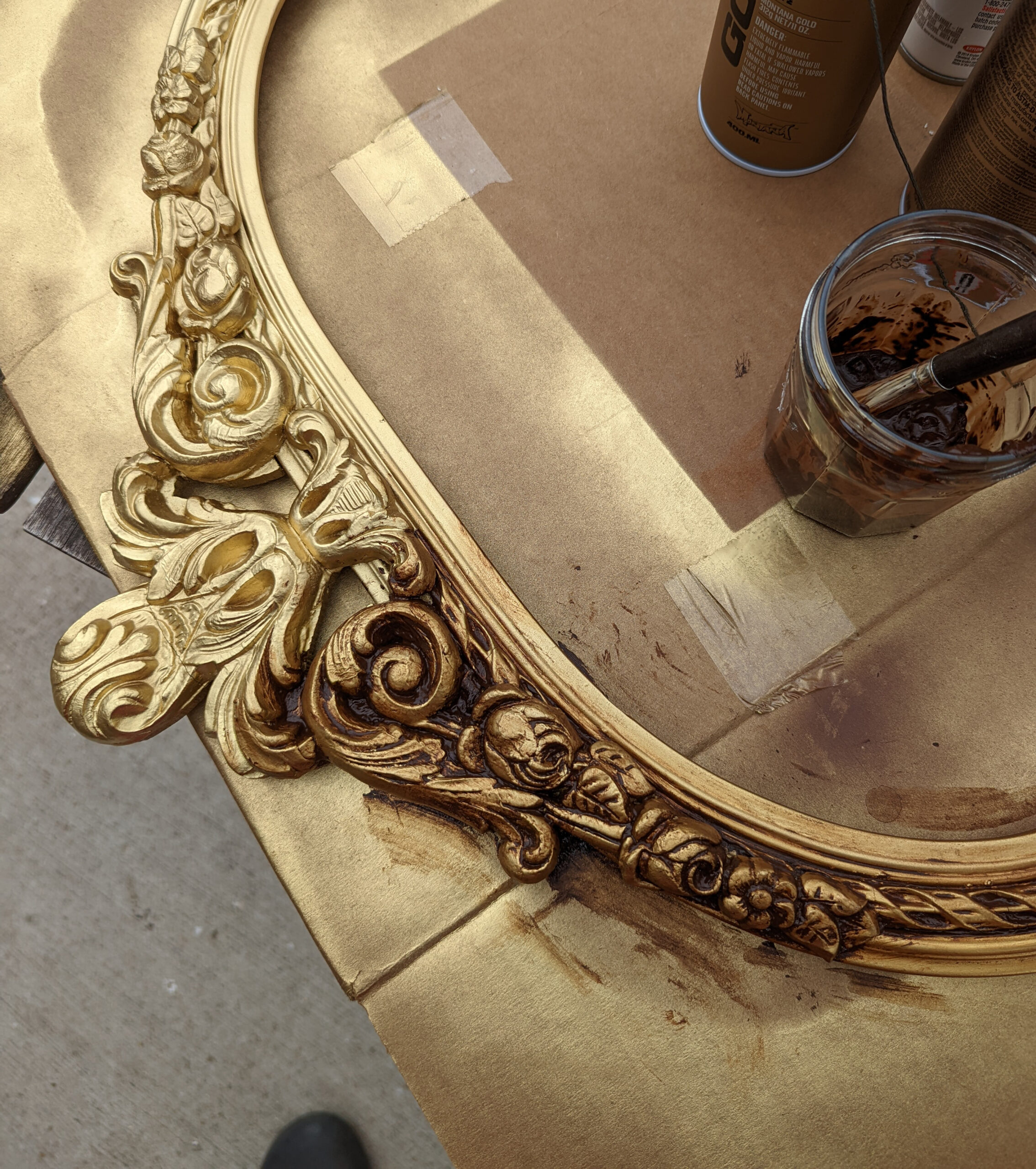 A closeup image of an antique frame being repainting with an antique gold finish.