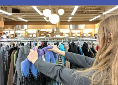 Text reading how to make a profit shopping thrift stores over an image of a woman holding up a sweater in a Goodwill.
