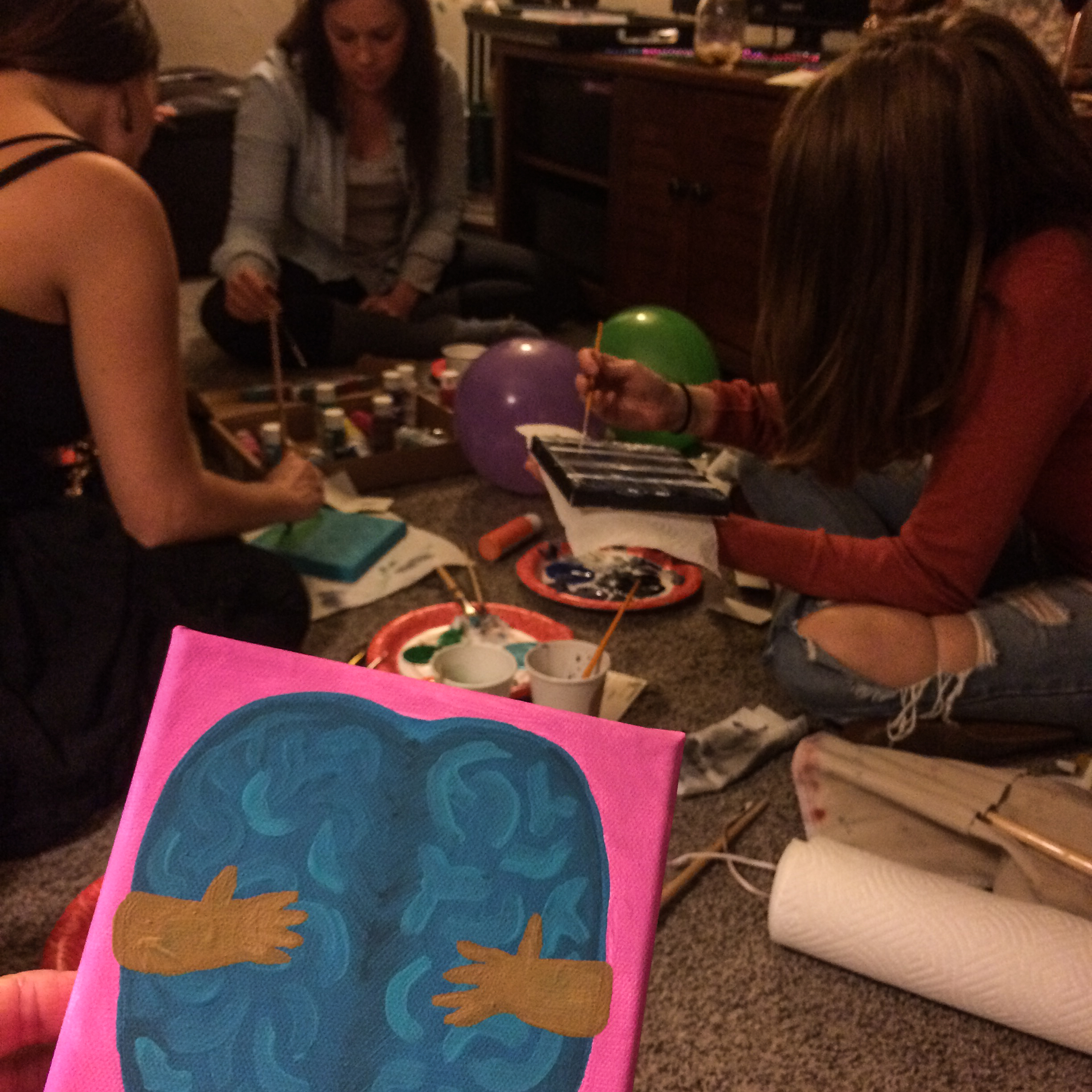 A group of paint and sip party attendees painting.